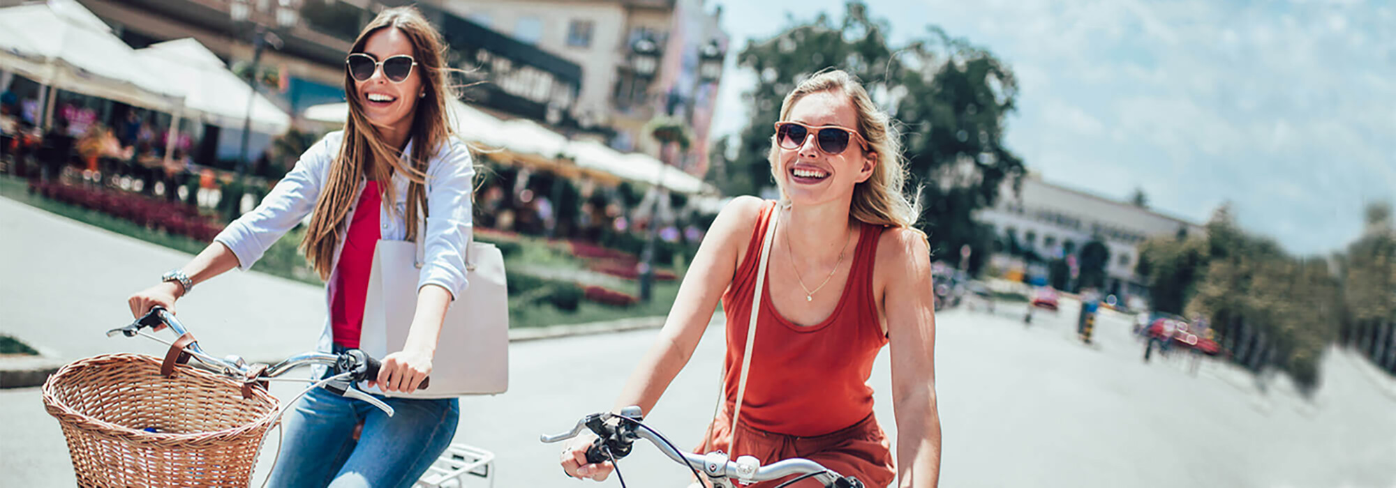 Zwei Damen auf einen Fahrrad sind auf der Straße zum Einkaufen unterwegs.